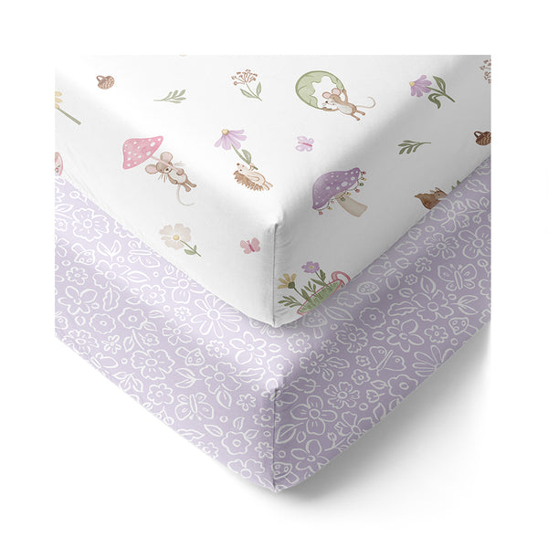Two fitted sheets for a cot, one with a whimsical animal pattern and the other in a solid purple color.